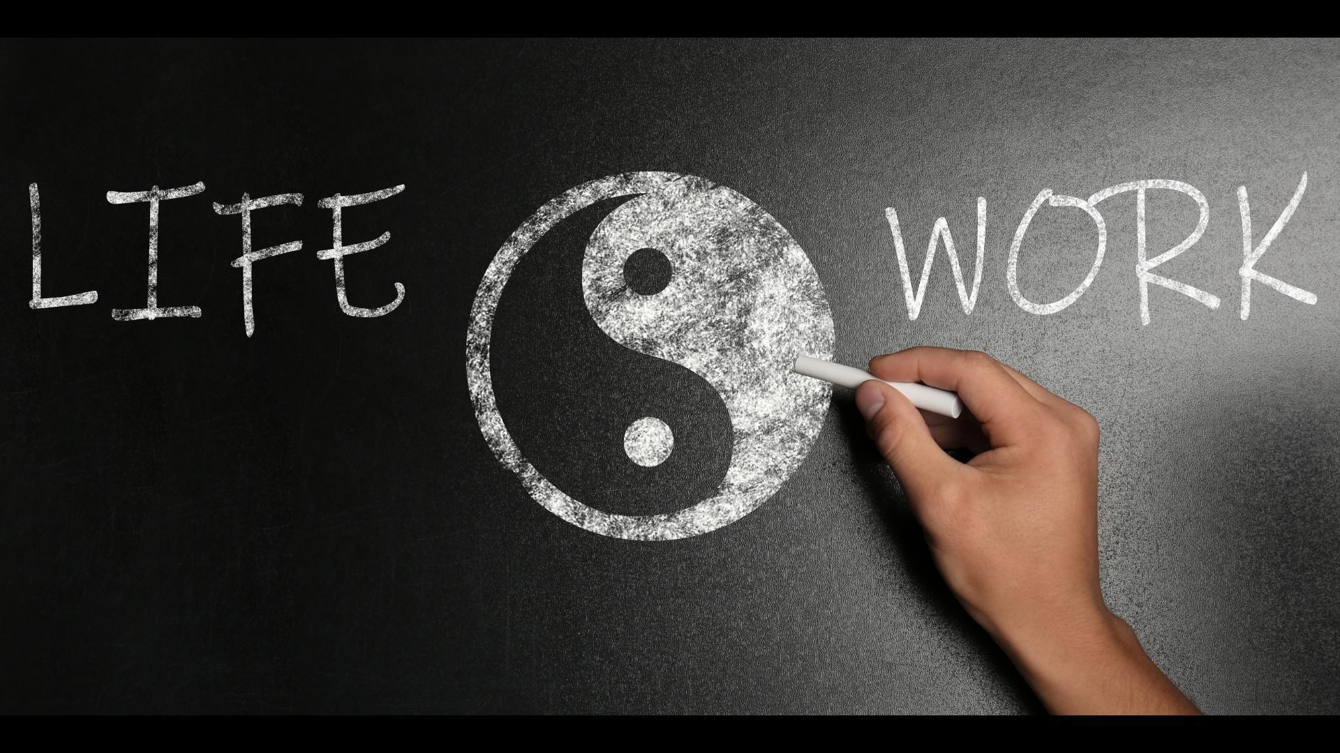 Les mots "Life" et "Work" sont de part et d'autres du symbole yin/yang dessiné à la craie par une main.